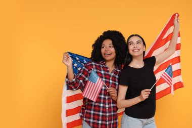 4 Temmuz - ABD 'nin Bağımsızlık Günü. Sarı arka planda Amerikan bayrakları olan mutlu kadınlar. Metin için boşluk