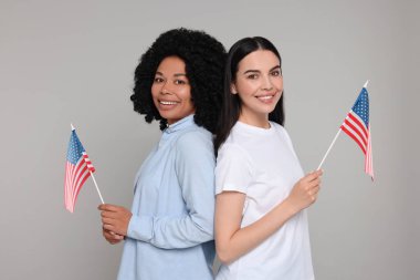 4 Temmuz - ABD 'nin Bağımsızlık Günü. Gri arka planda Amerikan bayrakları olan mutlu kadınlar