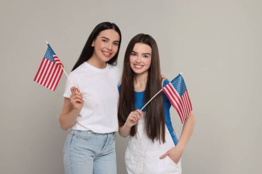 4 Temmuz - ABD 'nin Bağımsızlık Günü. Açık gri arka planda Amerikan bayrakları olan mutlu kadın ve kızı
