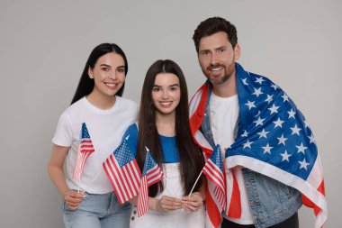 4 Temmuz - ABD 'nin Bağımsızlık Günü. Gri arka planda Amerikan bayrakları olan mutlu bir aile.