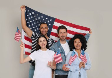 4 Temmuz - ABD 'nin Bağımsızlık Günü. Gri arka planda Amerikan bayrakları olan mutlu arkadaşlar
