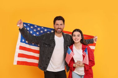 4 Temmuz - ABD 'nin Bağımsızlık Günü. Sarı arka planda Amerikan bayrakları olan mutlu bir adam ve kızı.