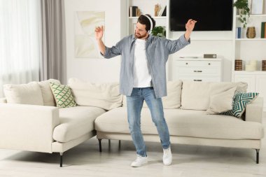 Emotional man dancing while listening music with headphones at home