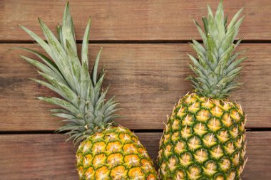 Tahta masanın üzerinde nefis olgun ananaslar, düz uzanmış.