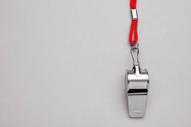 One metal whistle with red cord on light grey background, top view. Space for text clipart