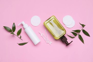 Farklı temizleyiciler, yapraklar, pembe arka planda pamuk tomurcukları ve pedler, metin için yeri olan düz yataklar. Kozmetik ürünü