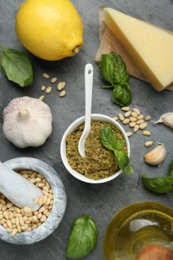 Lezzetli pesto sosu ve malzemeler gri masada, düz yerde.