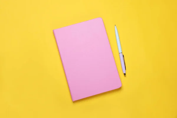 Κλειστό Ροζ Σημειωματάριο Και Στυλό Κίτρινο Φόντο Επίπεδη Lay — Φωτογραφία Αρχείου