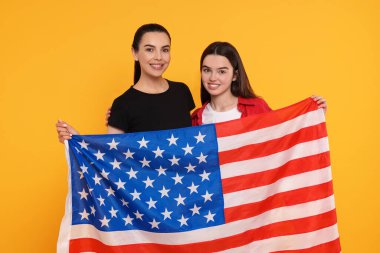 4 Temmuz - ABD 'nin Bağımsızlık Günü. Sarı arka planda Amerikan bayrağı olan mutlu kadın ve kızı