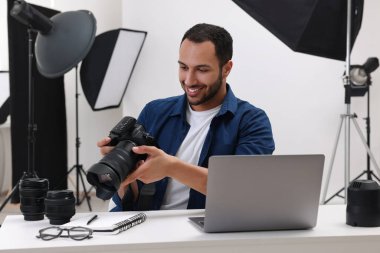 Modern fotoğraf stüdyosundaki masada kamerası olan genç profesyonel fotoğrafçı.