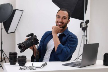 Modern fotoğraf stüdyosundaki masada kamerası olan genç profesyonel fotoğrafçı.