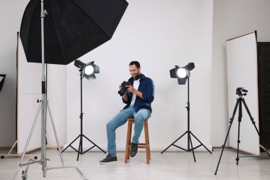 Modern fotoğraf stüdyosunda kamerası olan genç profesyonel fotoğrafçı.