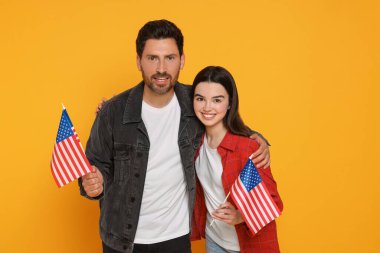 4 Temmuz - ABD 'nin Bağımsızlık Günü. Sarı arka planda Amerikan bayrakları olan mutlu bir adam ve kızı.