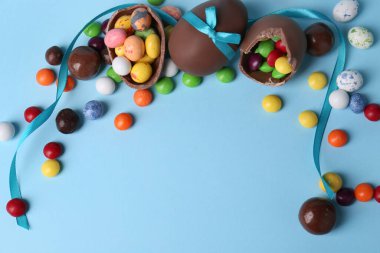 Lezzetli çikolatalı yumurtalar ve açık mavi arka planda farklı şekerler içeren kompozisyon. Metin için boşluk