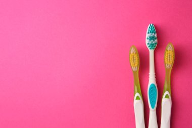 Pembe arka planda diş fırçaları, düz yatış. Metin için boşluk