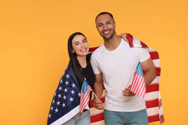 stock image 4th of July - Independence Day of USA. Happy couple with American flags on yellow background, space for text