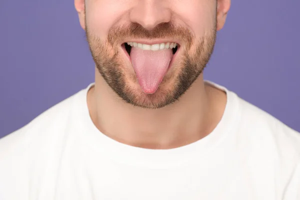 紫色の背景に彼の舌を示す男 クローズアップ — ストック写真