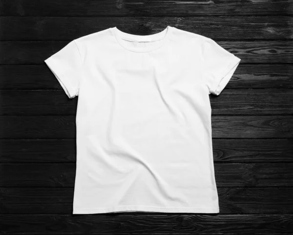 黒の木の背景にスタイリッシュな白いTシャツ トップビュー — ストック写真