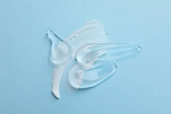 stock image Samples of cosmetic gel and cream on light blue background, top view