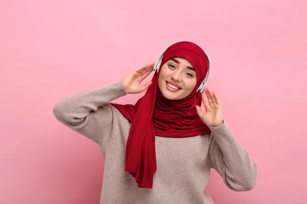 带头巾的穆斯林妇女画像和粉色背景的耳机 — 图库照片