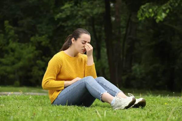 公園の緑の芝生で季節の春のアレルギーに苦しむ女性 — ストック写真