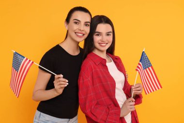 4 Temmuz - ABD 'nin Bağımsızlık Günü. Sarı arka planda Amerikan bayrakları olan mutlu kadın ve kızı