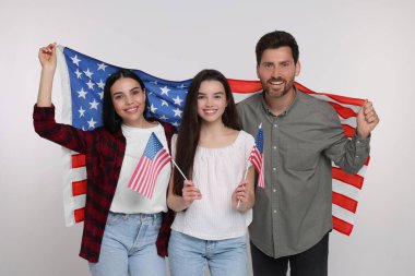 4 Temmuz - ABD 'nin Bağımsızlık Günü. Beyaz arka planda Amerikan bayrakları olan mutlu bir aile.