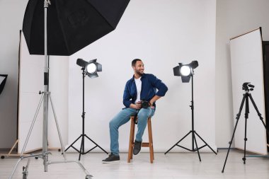 Modern fotoğraf stüdyosunda kamerası olan genç profesyonel fotoğrafçı.