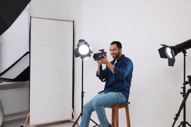 Modern fotoğraf stüdyosunda kamerası olan genç profesyonel fotoğrafçı.