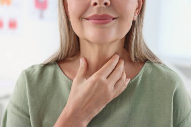 Endocrine system. Senior woman doing thyroid self examination indoors, closeup clipart