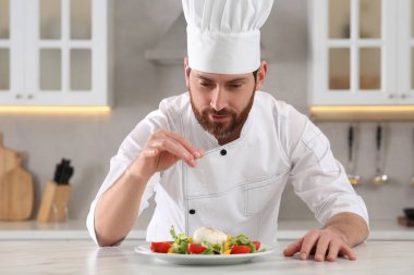 Profesyonel aşçı mutfaktaki mermer masada lezzetli salata yapıyor.