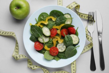 Ölçüm bandı, salata, elma ve çatal bıçak takımı.
