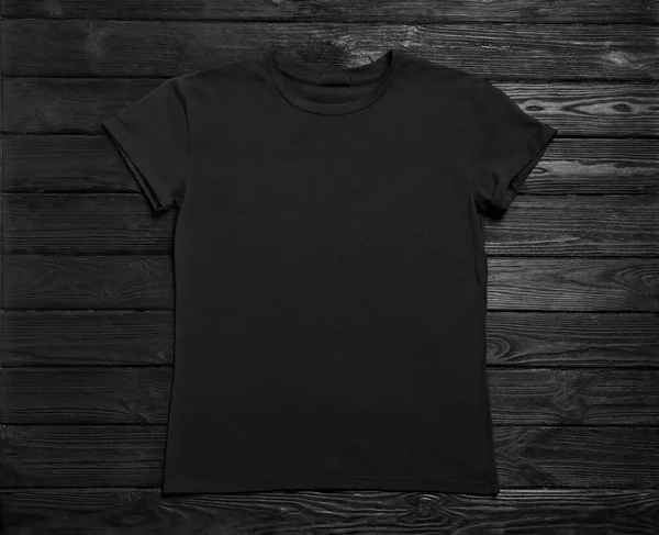 黒の木の背景にスタイリッシュなTシャツ トップビュー — ストック写真