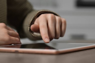Masada arka planda modern tablet kullanan bir kadının yakın görüntüsü