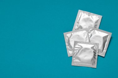 Açık mavi arkaplanda paketli prezervatifler, metin için en üstte boşluk. Güvenli seks.