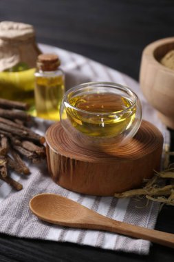 Meyan kökü esaslı yağ ve kaşık ile siyah masada kase.