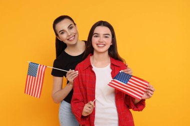 4 Temmuz - ABD 'nin Bağımsızlık Günü. Sarı arka planda Amerikan bayrakları olan mutlu kadın ve kızı