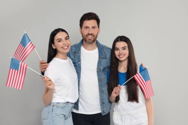 4 Temmuz - ABD 'nin Bağımsızlık Günü. Gri arka planda Amerikan bayrakları olan mutlu bir aile.