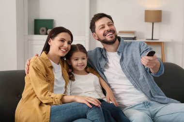 Evde film izleyen mutlu bir aile. Babam uzaktan kumandayla televizyon kanallarını değiştiriyor.