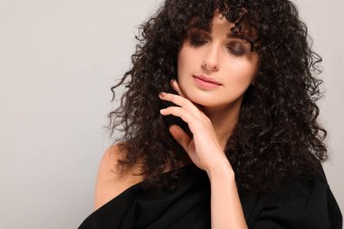 Açık gri arka planda uzun kıvırcık saçlı güzel bir genç kadın. Metin için boşluk