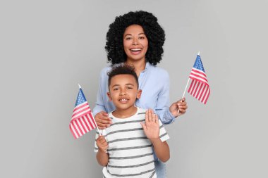 4 Temmuz - ABD 'nin Bağımsızlık Günü. Açık gri arka planda Amerikan bayrakları olan mutlu kadın ve oğlu