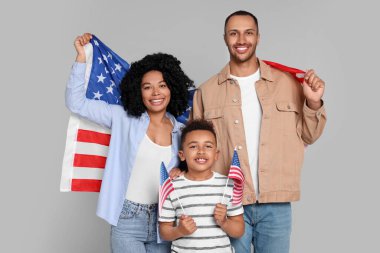 4 Temmuz - ABD 'nin Bağımsızlık Günü. Açık gri arka planda Amerikan bayrakları olan mutlu bir aile.