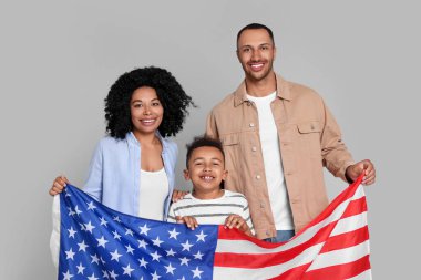 4 Temmuz - ABD 'nin Bağımsızlık Günü. Açık gri arka planda Amerikan bayrağı taşıyan mutlu bir aile.