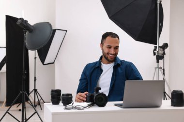 Modern fotoğraf stüdyosunda dizüstü bilgisayarda çalışan genç profesyonel fotoğrafçı.