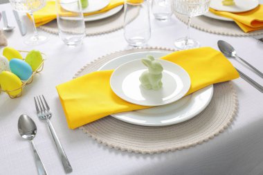 Festive table setting with cutlery, plate and bunny figure. Easter celebration