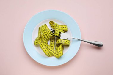 Pembe arka planda çatal ve şerit, üst manzara. Kilo verme konsepti