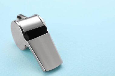 Açık mavi arka planda metal bir düdük, yakın plan. Metin için boşluk