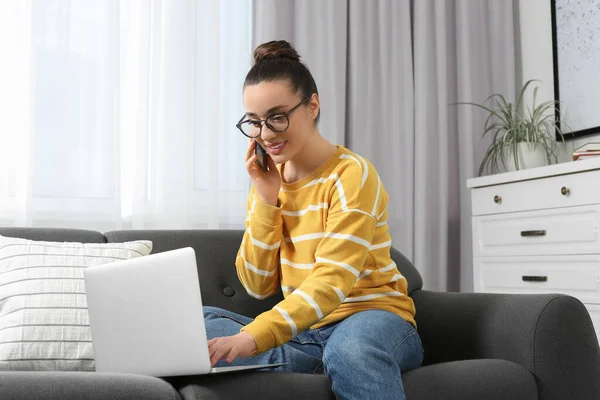 家庭工作场所在房间里一边用笔记本电脑一边用智能手机聊天的快乐女人 — 图库照片