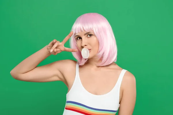 Beautiful woman blowing bubble gum and gesturing on green background