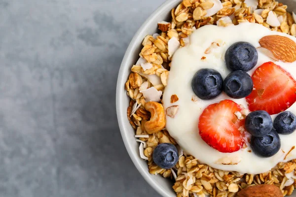味道鲜美的格拉诺拉 酸奶和新鲜的浆果在浅灰的桌子上的碗 顶部视图与文字的空间 健康早餐 — 图库照片